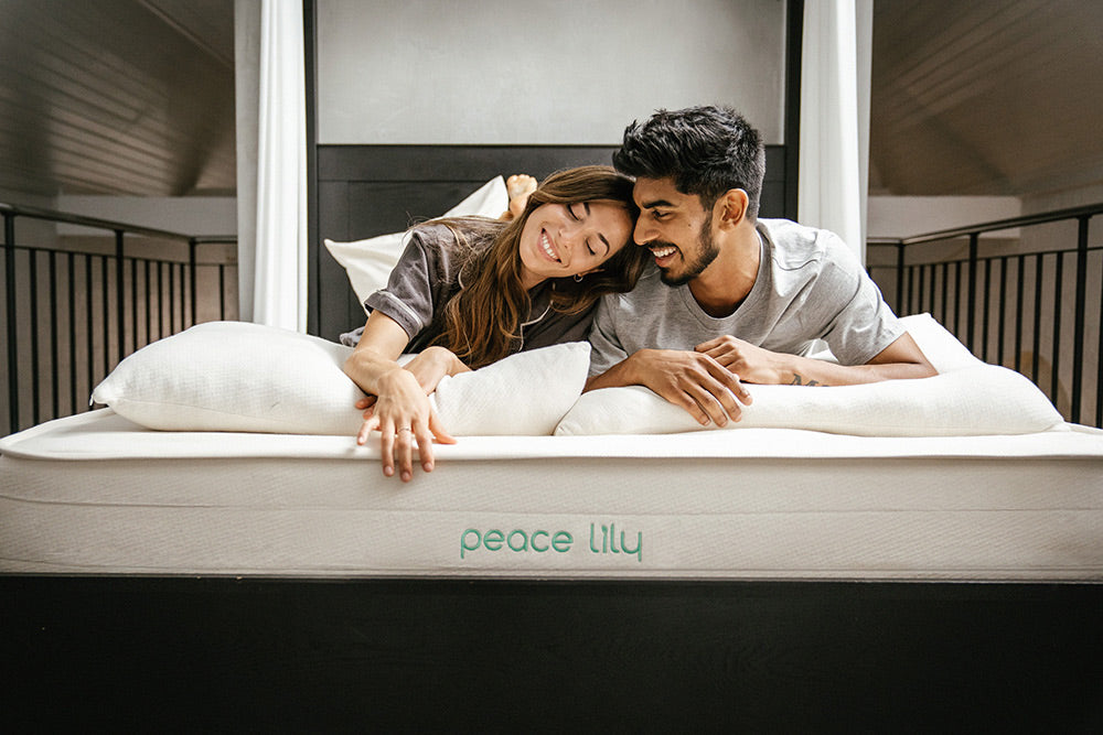 A man and a woman lie smiling on a Peacelily bed