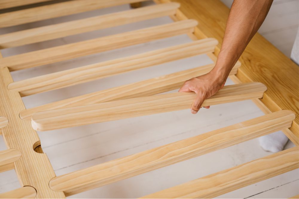 Hand fitting a timber slat into the Peace Lily Timber Bed Frame during assembly