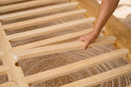 Hand positioning a timber slat on the Peace Lily Timber Bed Frame during assembly
