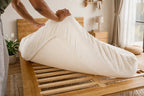 Person unrolling a Peace Lily latex mattress onto the Timber Bed Frame's slatted base
