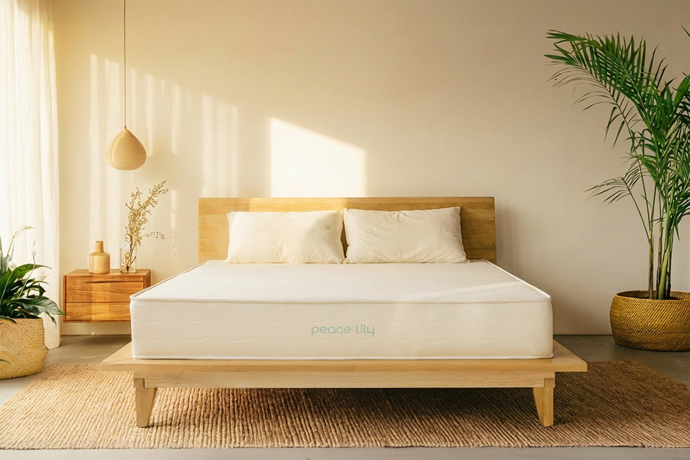 Peace Lily latex mattress with pillows on a wooden bed in a sunlit bedroom