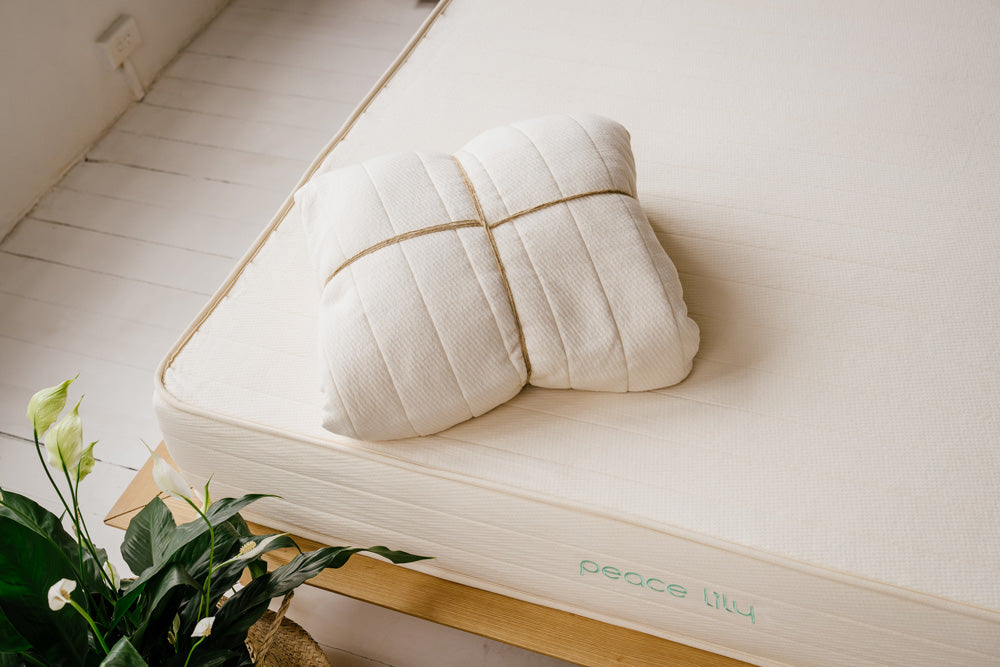 Folded organic cotton mattress protector on a wooden surface with a twine tie